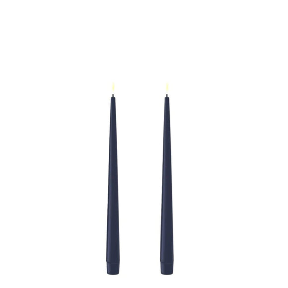 Photo of 2 Royal Blue (nearly Navy) 28cm tapered dinner candles. Their led flames are lit and they have black wicks.