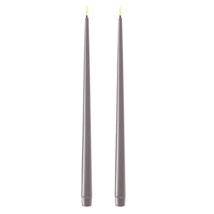 Photo of 2 warm Grey 38cm tapered dinner candles. Their led flames are lit and they have black wicks.