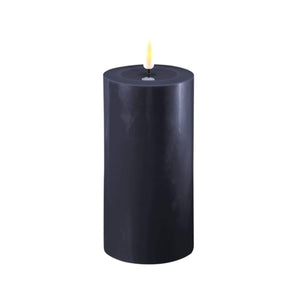 Photo of a Deluxe HomeArt Royal Blue LED Pillar candle that is 7.5cm wide and 15cm tall. At the top of the candle is a clear resign pool that looks like a pool of melted wax. The flame is white and orange and is on a black wick.