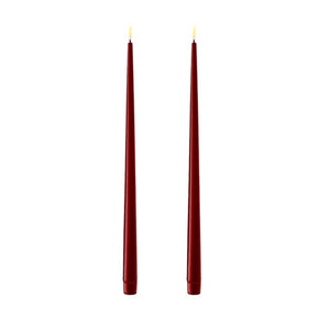 Photo of 2 bourgogne red (deep burgundy) 38cm tapered dinner candles. Their led flames are lit and they have black wicks.