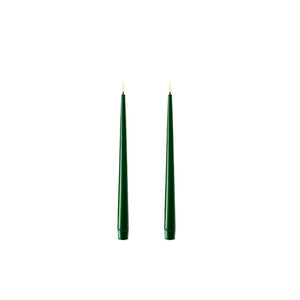 Photo of 2 dark green 28cm tapered dinner candles. Their led flames are lit and they have black wicks.