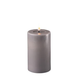 Image of a 12.5cm tall mocha coloured led candle. The wick is black and the electric flame is lit. Around the base of the wick is a transparent wax pool.