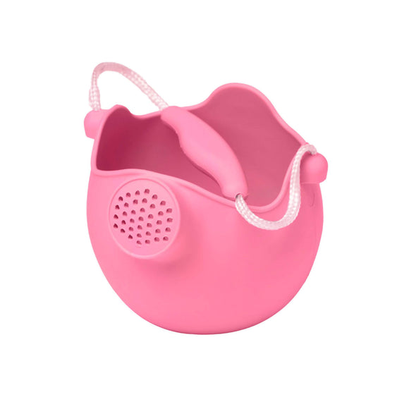 Photo of the Scrunch Watering Can in Flamingo Pink. This silicone watering can is shaped like a sphere, with the top taken off in a wavy way. A spout slightly protrudes just below the edge on one side. The handle is made from rope with a bit of matching silicone at the top for easier holding.